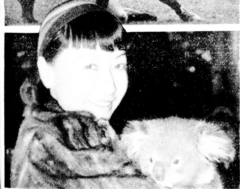 Anna May Wong smiling, in a fur coat, holding a baby koala.